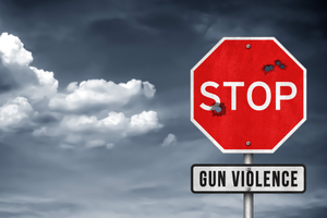 Photo of red stop sign with additional sign added underneath reading "Gun Violence" and gray skies in the background