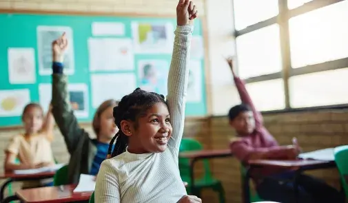 young black girl in foreground raises hand with smile on her face