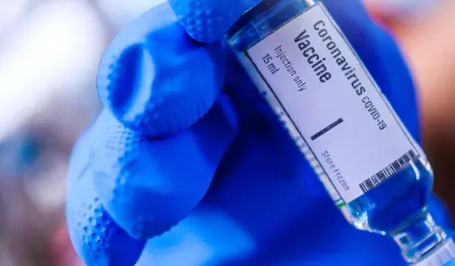 vaccine being given by hand in blue glove