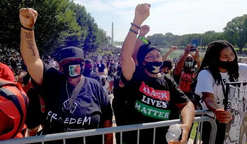 people raise their fists with the washington monument in the background