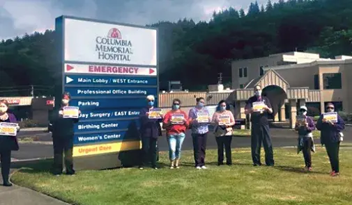 nurses stand outside with hospital sign