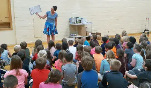 Photo of adult reading to a room full of children