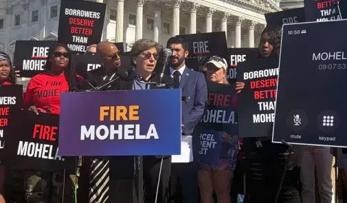 AFT President Randi Weingarten speaking to press at an outdoor conference surrounded by signs and people supporting the FIRE MOHELA movement