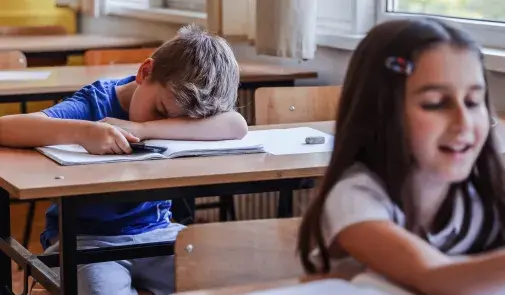 exhausted elementary school student asleep at desk