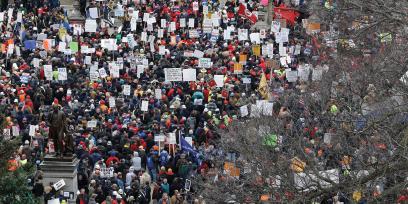 A giant crowd of people holding pro-labor signs on the steps and lawn of the Michigan State House, protesting the 2012 anti-union laws that had just been passed.