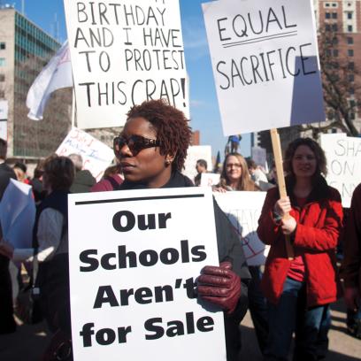 woman holds sign saying "Our Schools Aren't for Sale" at a 2013 pro-union rally